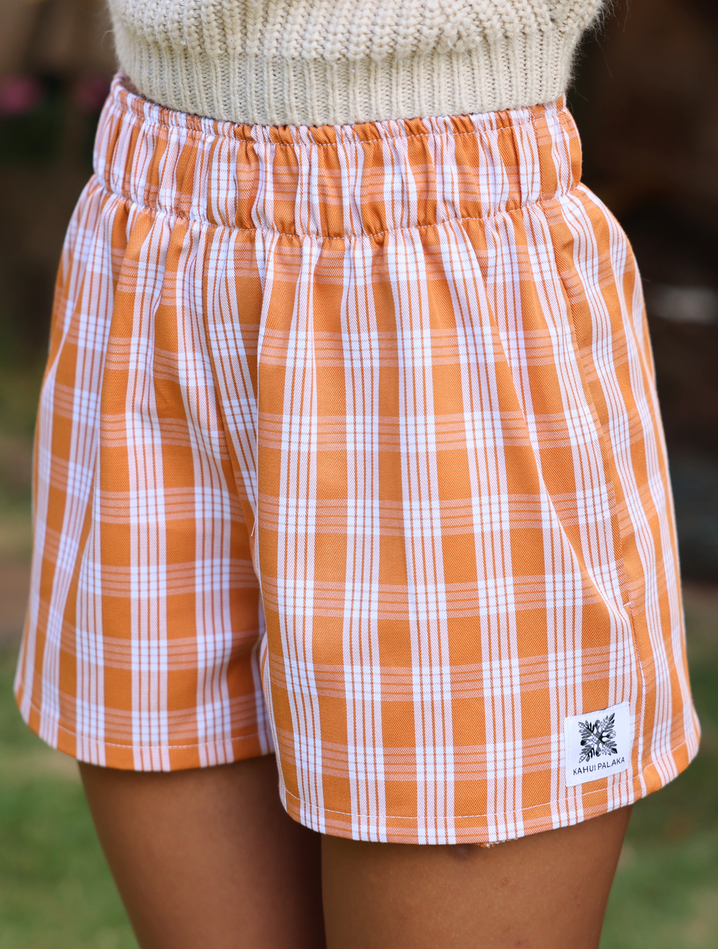 Wahine Holoholo Shorts 2.0 in Kaunaʻoa Rust showcase a Palaka print with an elastic waistband. The knit top adds cozy contrast.