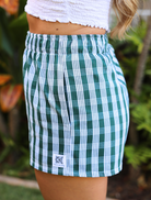 Wahine Holoholo Shorts 2.0 in a traditional Palaka pattern. Side view with elastic waistband. Bright outdoor lighting.