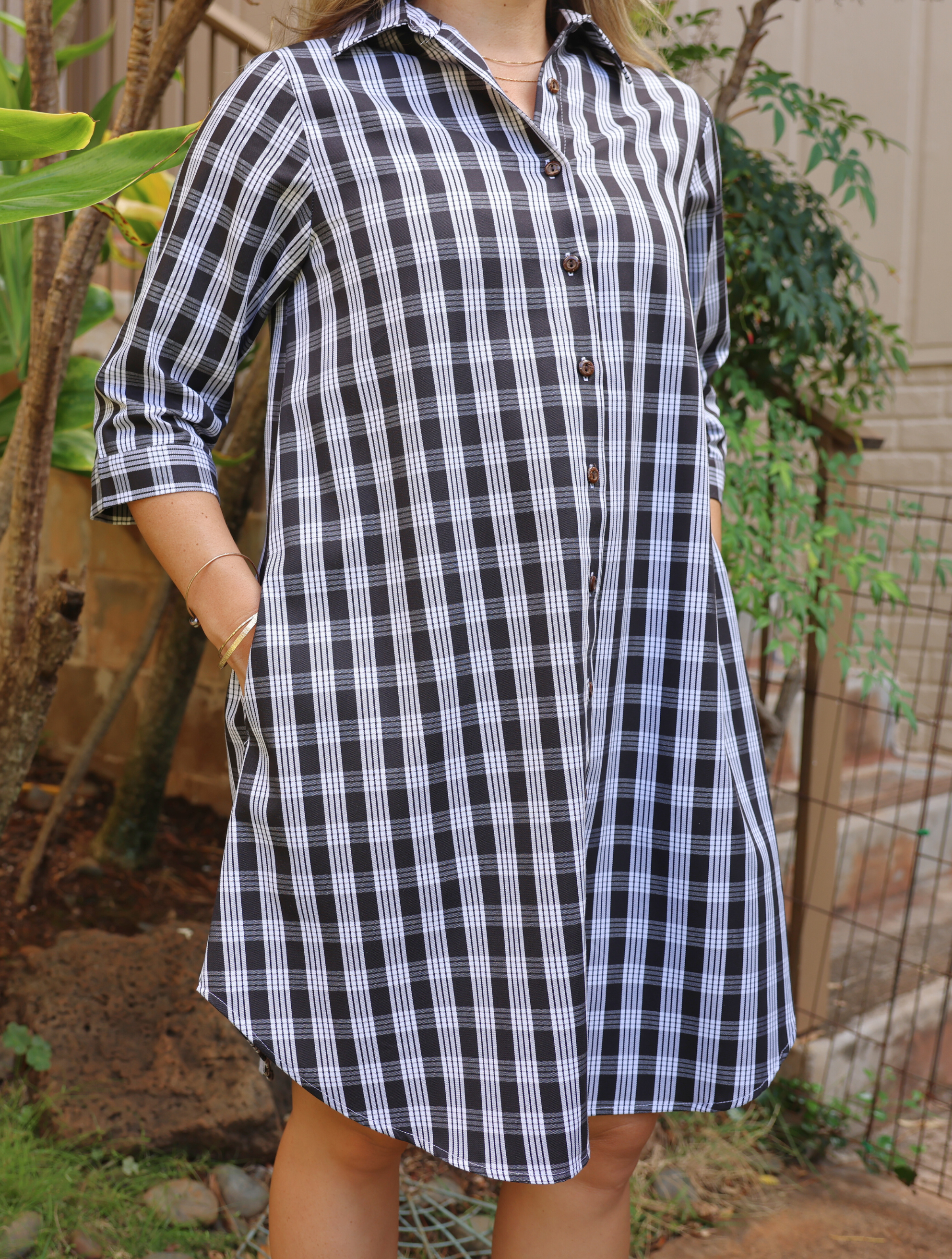 Moana Collection Dress featuring traditional Palaka pattern. Model poses with hands in pockets. Sleeves rolled to elbow.