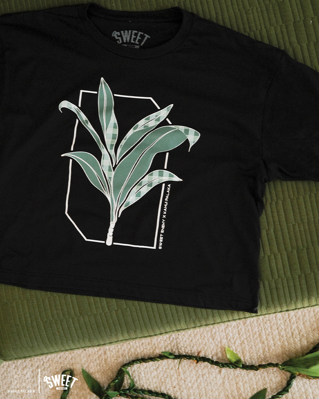 Black crop T-shirt featuring a green leafy design with Palaka print accents, styled against a subtle background.